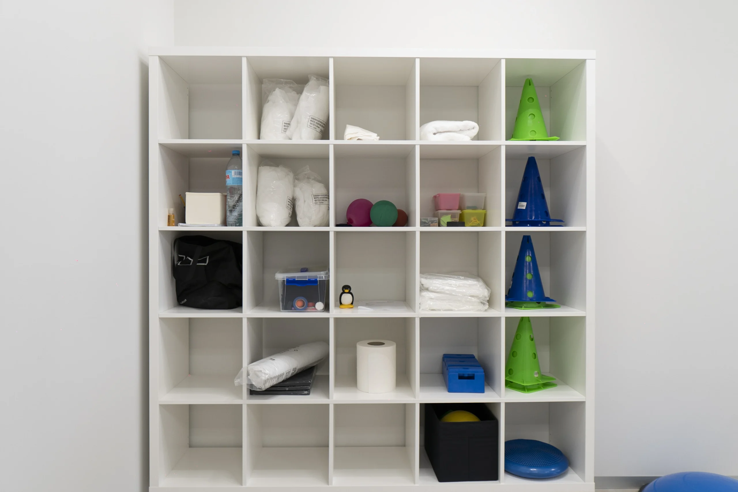 Estantería organizada con material terapéutico y de rehabilitación en Premium Centro Médico, incluyendo conos, pelotas, vendas y accesorios especializados.